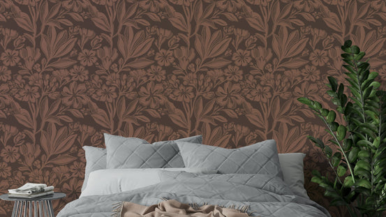 Terracotta Bloom wallpaper with rust floral damask behind a gray quilted bed and green ZZ plant in a bedroom