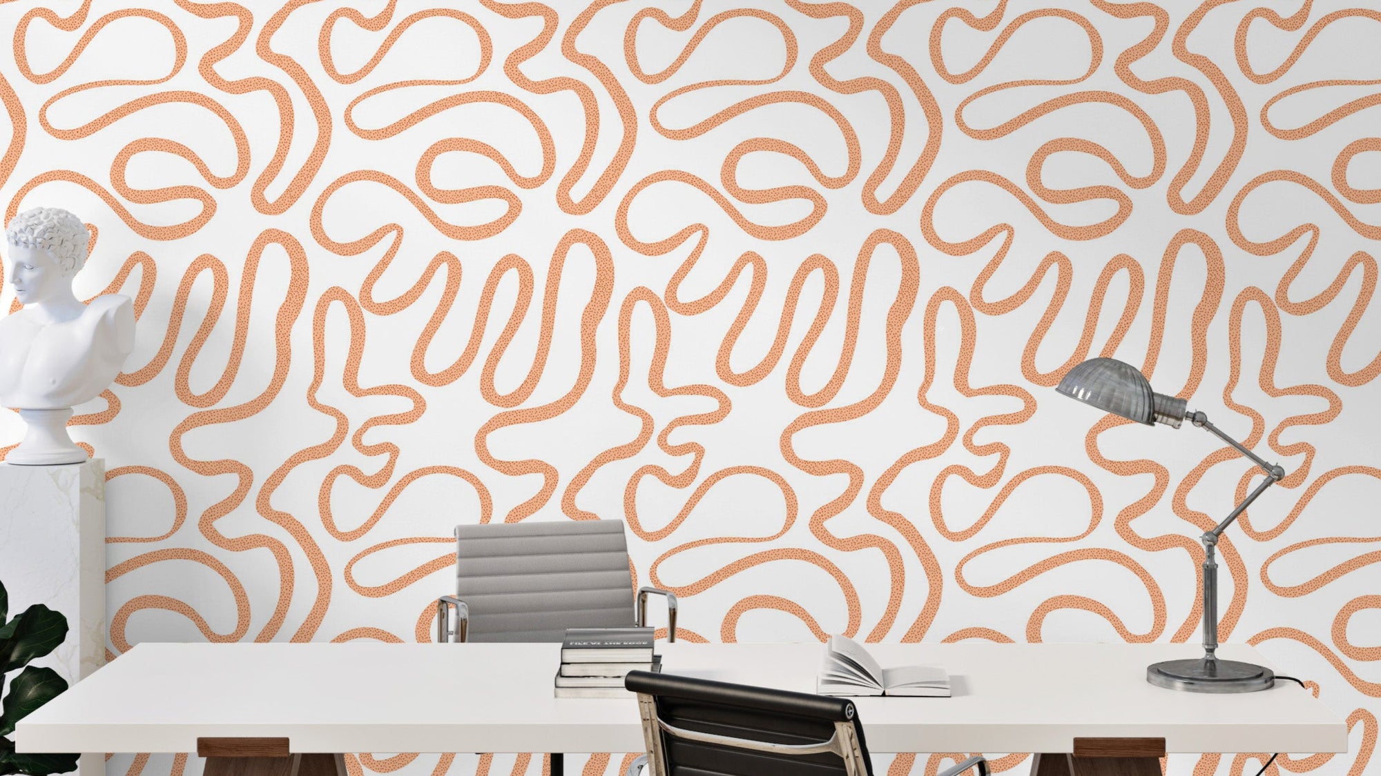 Terracotta Flow wallpaper with abstract orange squiggle lines on white in a home office with a desk, bust sculpture and lamp