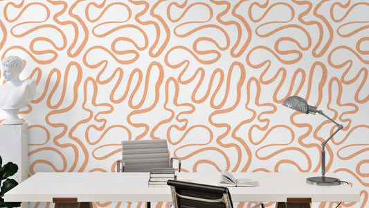 Terracotta Flow wallpaper with abstract orange squiggle lines on white in a home office with a desk, bust sculpture and lamp