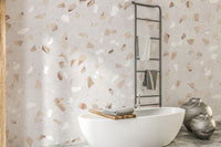 Terrazzo Marble Tile wallpaper mural with tan and white chips behind a white bathtub and black towel ladder