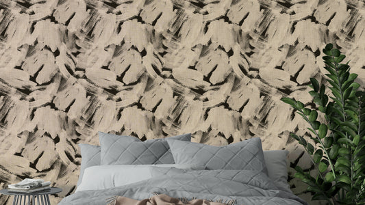 Textured Abstract Brushstroke wallpaper in beige and black behind a gray quilted bed and plant in a bedroom