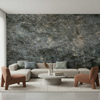 Textured Rock wallpaper mural in grey stone behind a beige sectional sofa and two terracotta armchairs