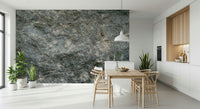 Textured Rock wallpaper mural in grey stone behind a wood dining table and wishbone chairs in a white kitchen
