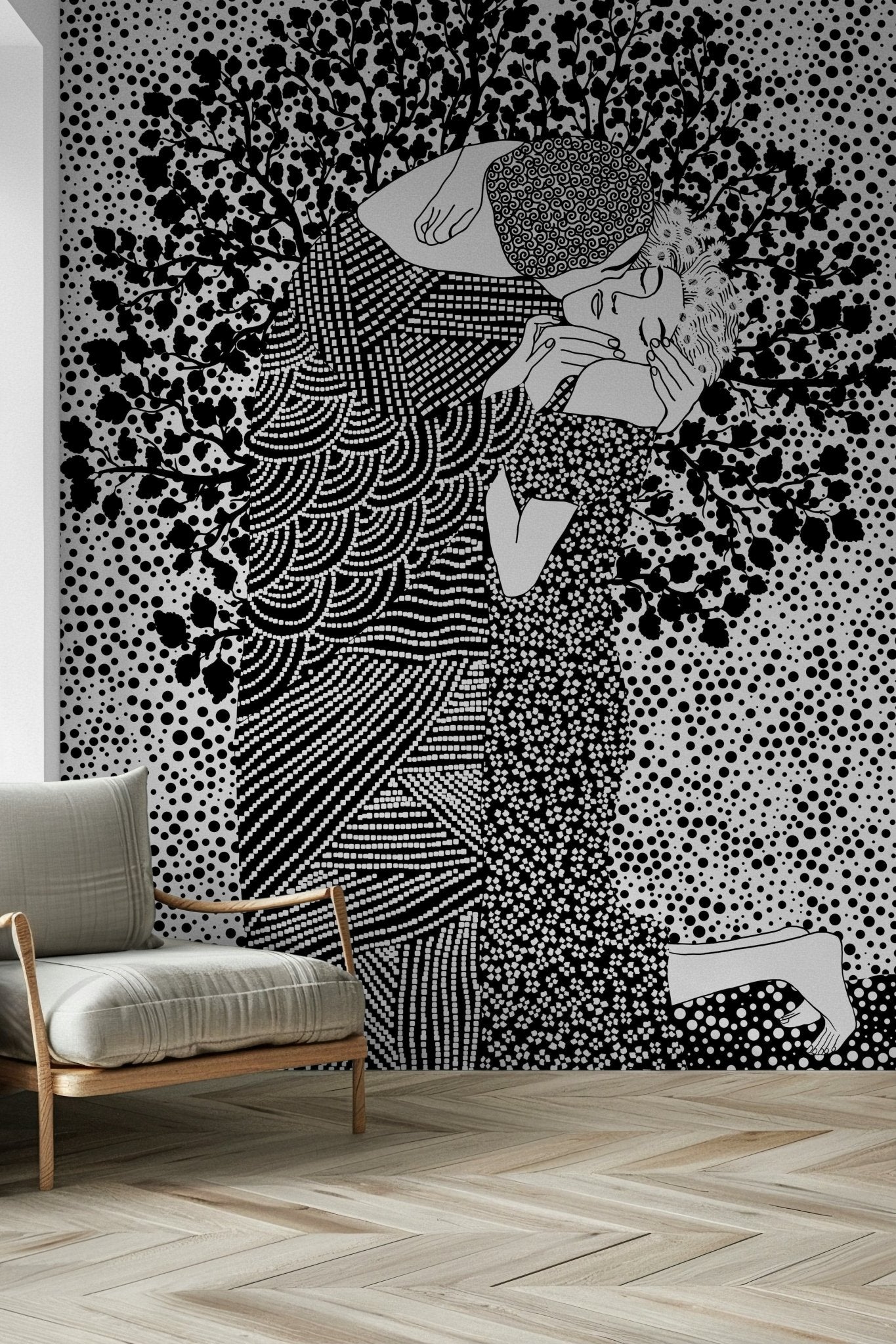 The Kiss II wallpaper mural of an embracing couple in black and white behind a beige wood-frame armchair