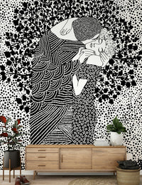 The Kiss II wallpaper mural of a black and white embracing couple above a wood credenza with plants