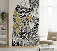 The Kiss wallpaper mural in black white and gold by white shelving and a beige armchair