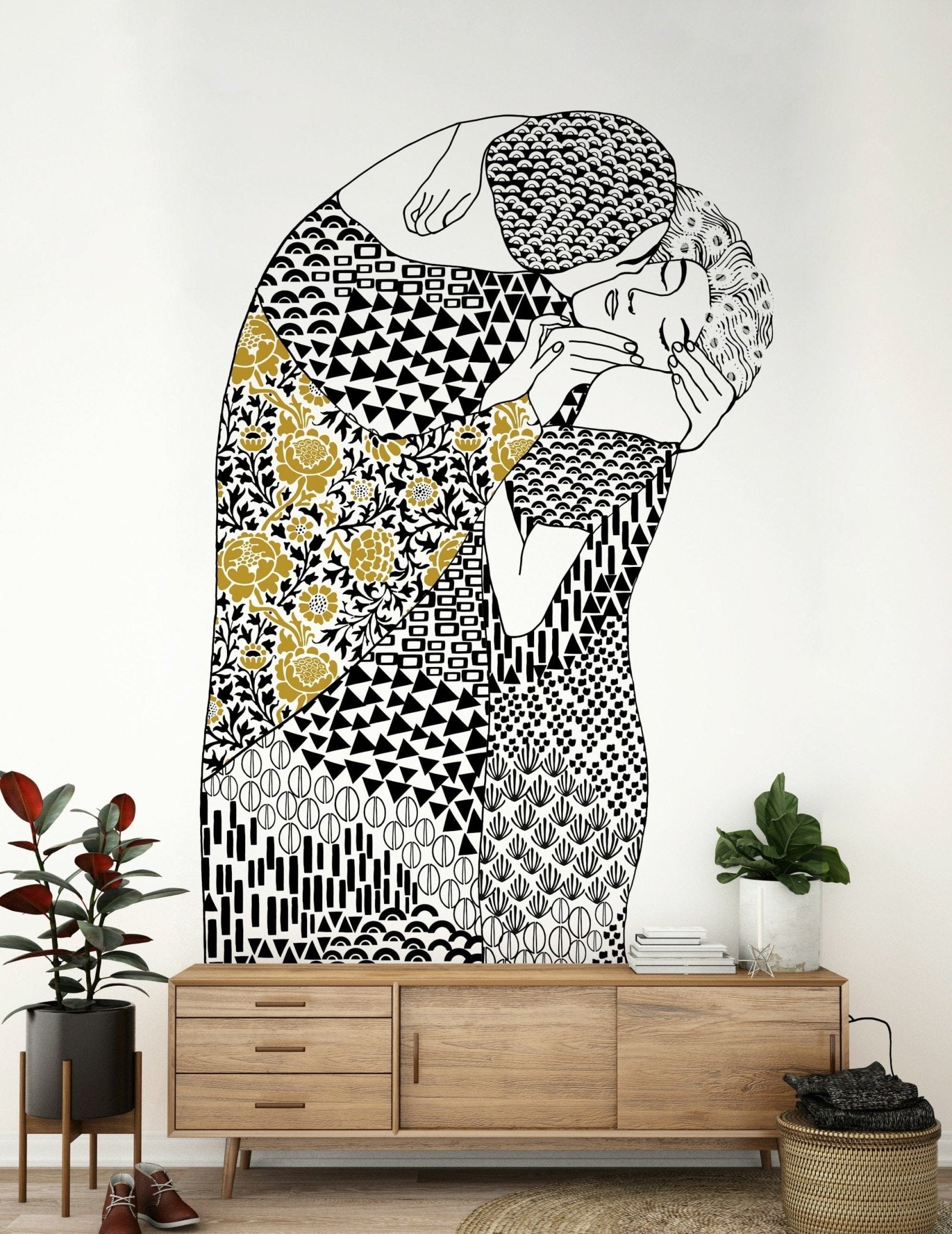 The Kiss wallpaper mural of an embracing couple above a wood sideboard with a rubber plant