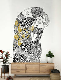 The Kiss wallpaper mural of an embracing couple above a wood sideboard with a rubber plant