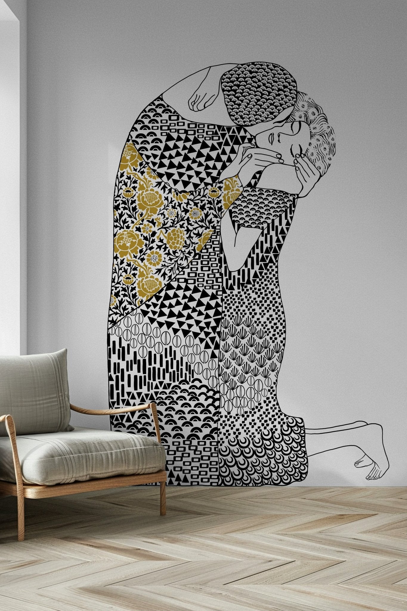 The Kiss wallpaper mural of an embracing couple beside a cream armchair on a herringbone floor