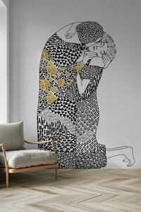 The Kiss wallpaper mural of an embracing couple beside a cream armchair on a herringbone floor