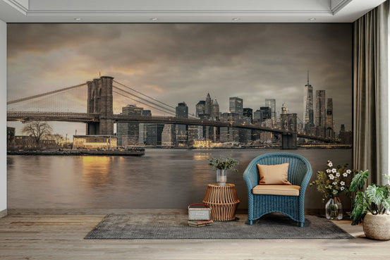 The Majestic Brooklyn Bridge wallpaper mural at dusk behind a blue wicker armchair in a cozy living room