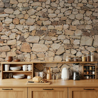 Timeless Stonework wallpaper mural of rounded tan fieldstone above a wood kitchen counter with dishes and kettle