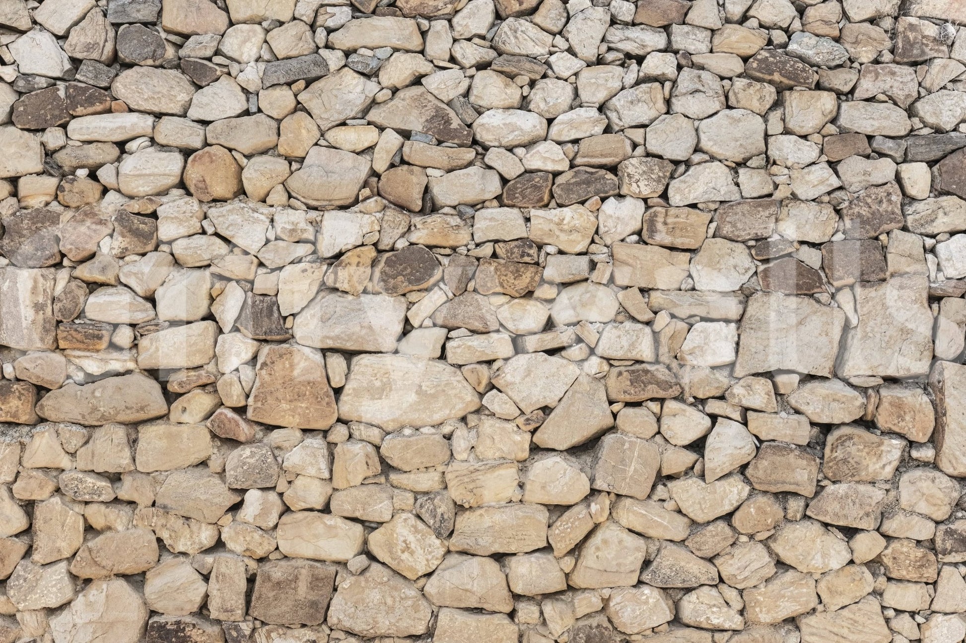 Timeless Stonework wallpaper mural close-up showing tan, cream and grey rounded fieldstone packed in tight mortar