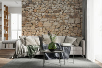 Timeless Stonework wallpaper mural of tan fieldstone behind a beige sofa with a sage throw and protea in a living room