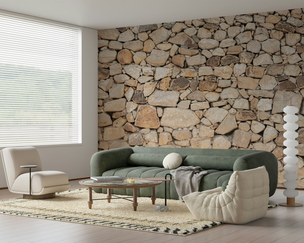 Timeless Stonework wallpaper mural of tan fieldstone behind a green sofa and cream chair in a bright living room