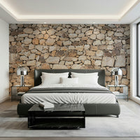 Timeless Stonework wallpaper mural in tan fieldstone behind a dark grey leather bed with chrome lamps in a bedroom