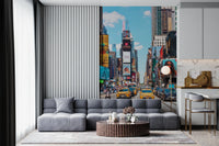 Times Square Buzz wallpaper mural of NYC taxis and billboards behind a gray modular sofa and fluted round table