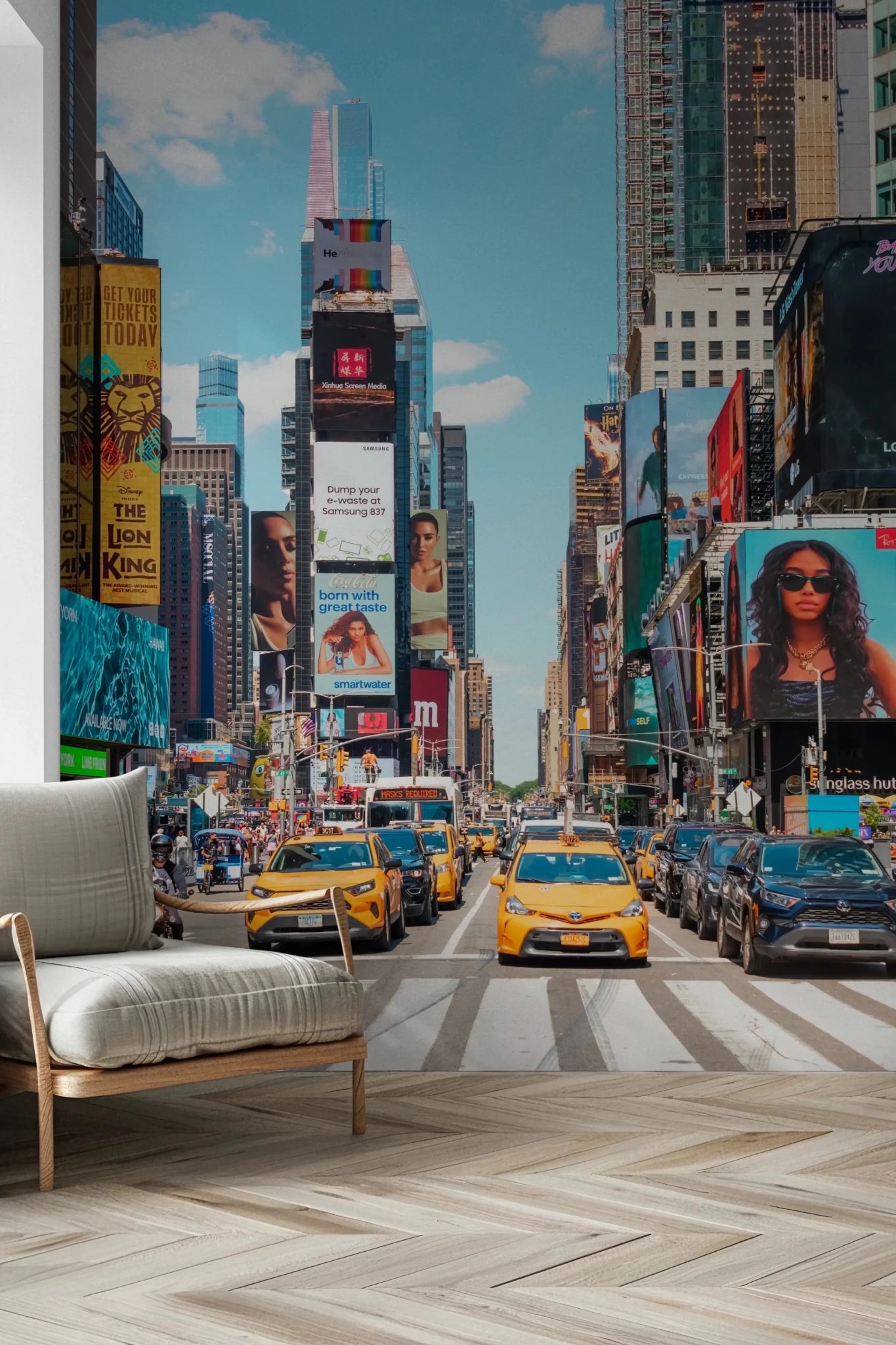Times Square Buzz wallpaper mural of yellow cabs crossing Times Square beside a beige armchair on a herringbone floor