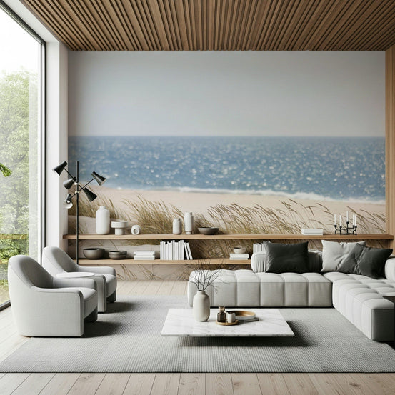 Beach Grass Hues wallpaper mural of dune grass and blue sea behind a gray sectional in a wood-ceiling living room