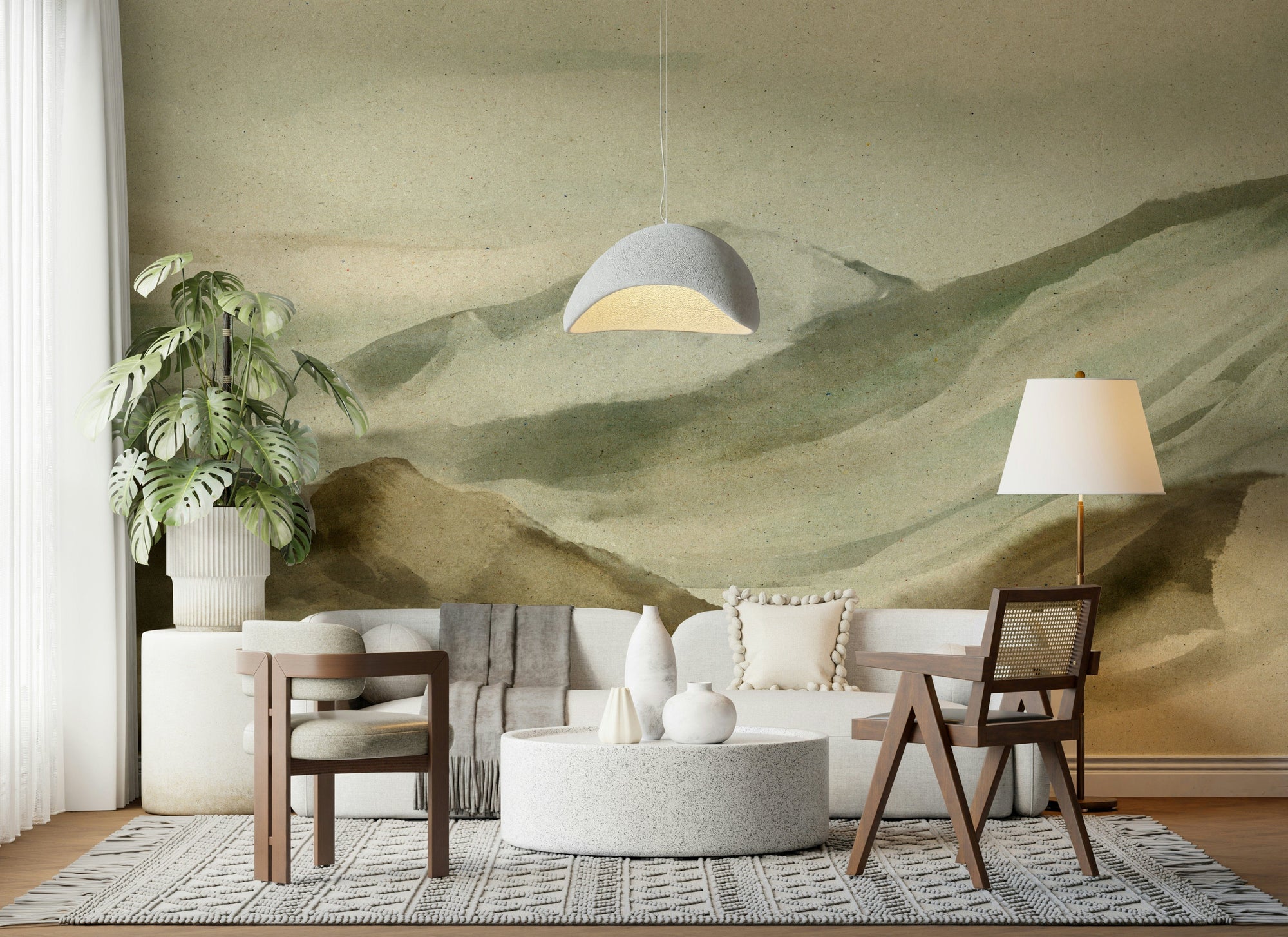 Watercolor Mountainscape wallpaper mural of sage green hills behind a white sofa and cane chair in a living room