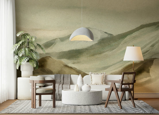 Watercolor Mountainscape wallpaper mural of sage green hills behind a white sofa and cane chair in a living room