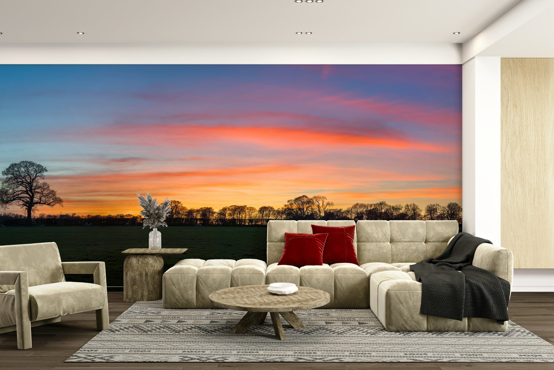 Serenity in Shadows wallpaper mural with twilight sky and treeline behind a beige sectional sofa and red cushions in a living room