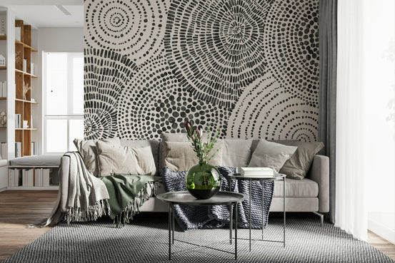 Tribal Rhythms wallpaper mural of black dotted circles behind a beige sofa with green throws in a lounge