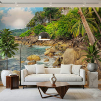 Tropical Shores wallpaper mural with a rocky palm-lined coastline behind a white sofa in a bright living room