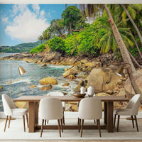 Tropical Shores wallpaper mural of a rocky palm bay behind a wood dining table and cream chairs in a dining room