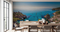 Turquoise Cove Escape wallpaper mural with sailboats and cliffs behind a wood dining table and sideboard