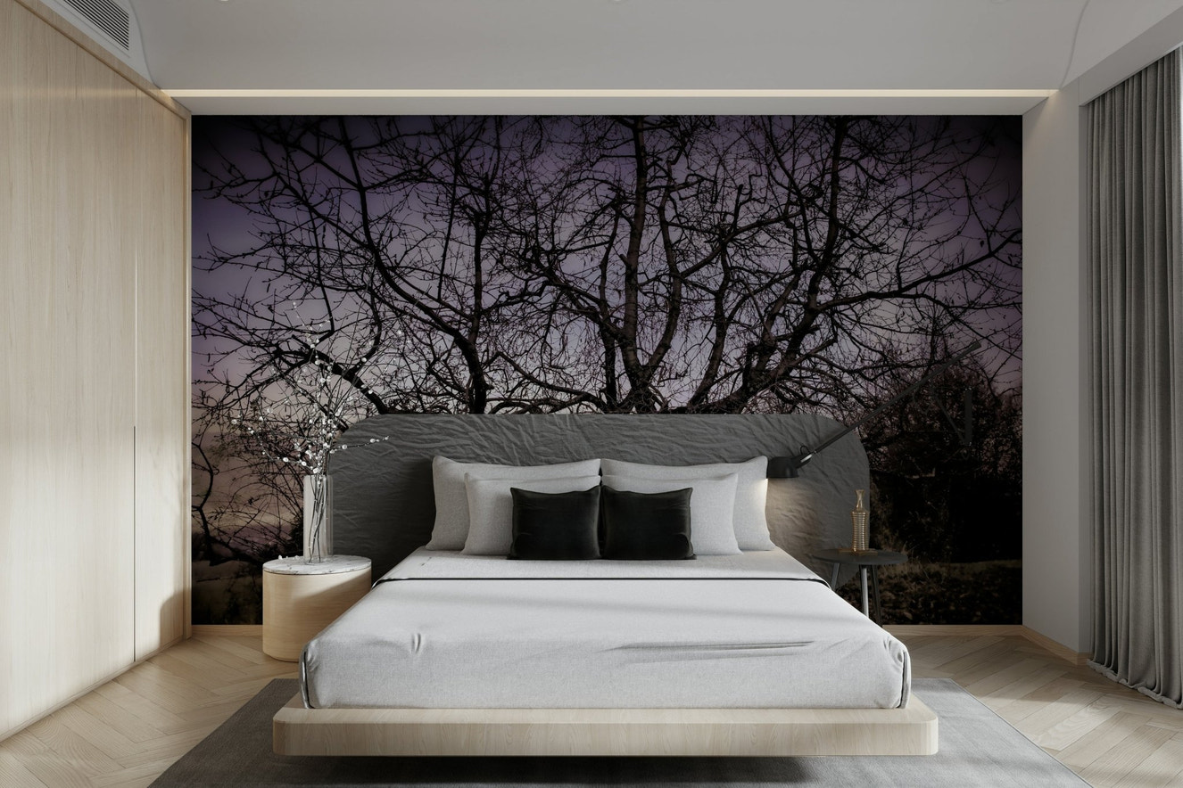 A black-and-white wall mural of a twisted, barren tree silhouette.
