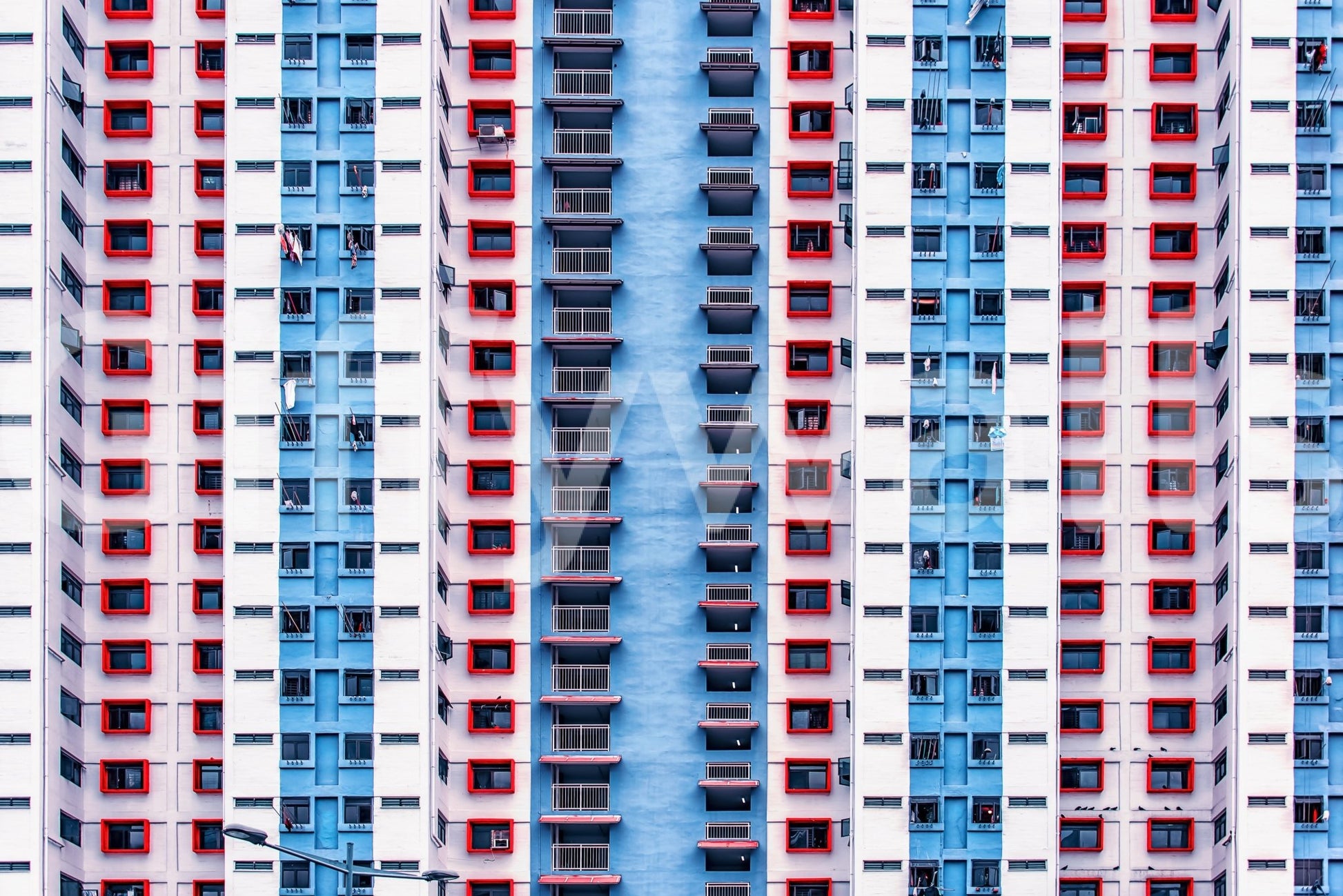 Urban Gridlock wallpaper mural shown as a full-wall facade of repeating red, white and blue apartment windows