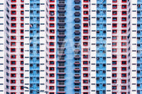 Urban Gridlock wallpaper mural shown as a full-wall facade of repeating red, white and blue apartment windows