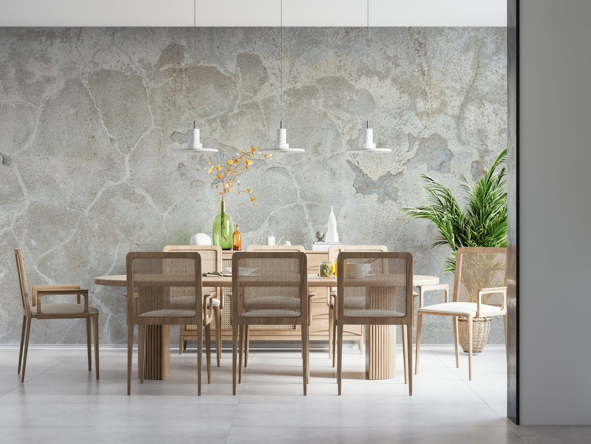 Urban Texture wallpaper mural in gray plaster behind a light wood dining table and cane chairs with a palm