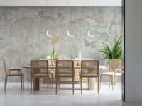 Urban Texture wallpaper mural in gray plaster behind a light wood dining table and cane chairs with a palm