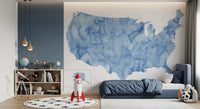 USA map with states and capitals in blue watercolor wallpaper mural in a kids bedroom with a navy bed and rocket toy