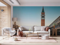Venetian Sunrise wallpaper mural of the Venice Campanile above a cream sofa with rust pillows and a fluffy chair