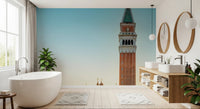 Venetian Sunrise wallpaper mural of St Mark's bell tower beside a freestanding tub and wood double vanity in a bathroom