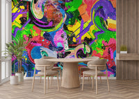 Vibrant Graffiti Splash wallpaper mural of neon paint splatters and swirls behind a round wood dining table and beige chairs