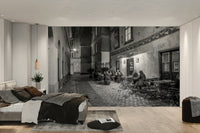 Street cafe in Vienna wallpaper mural of a black and white cobbled cafe alley behind a low grey bed in a bedroom