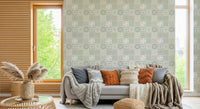 Vintage Folk Tiles Sage Green wallpaper behind a grey sofa with rust cushions by a wood window in a living room