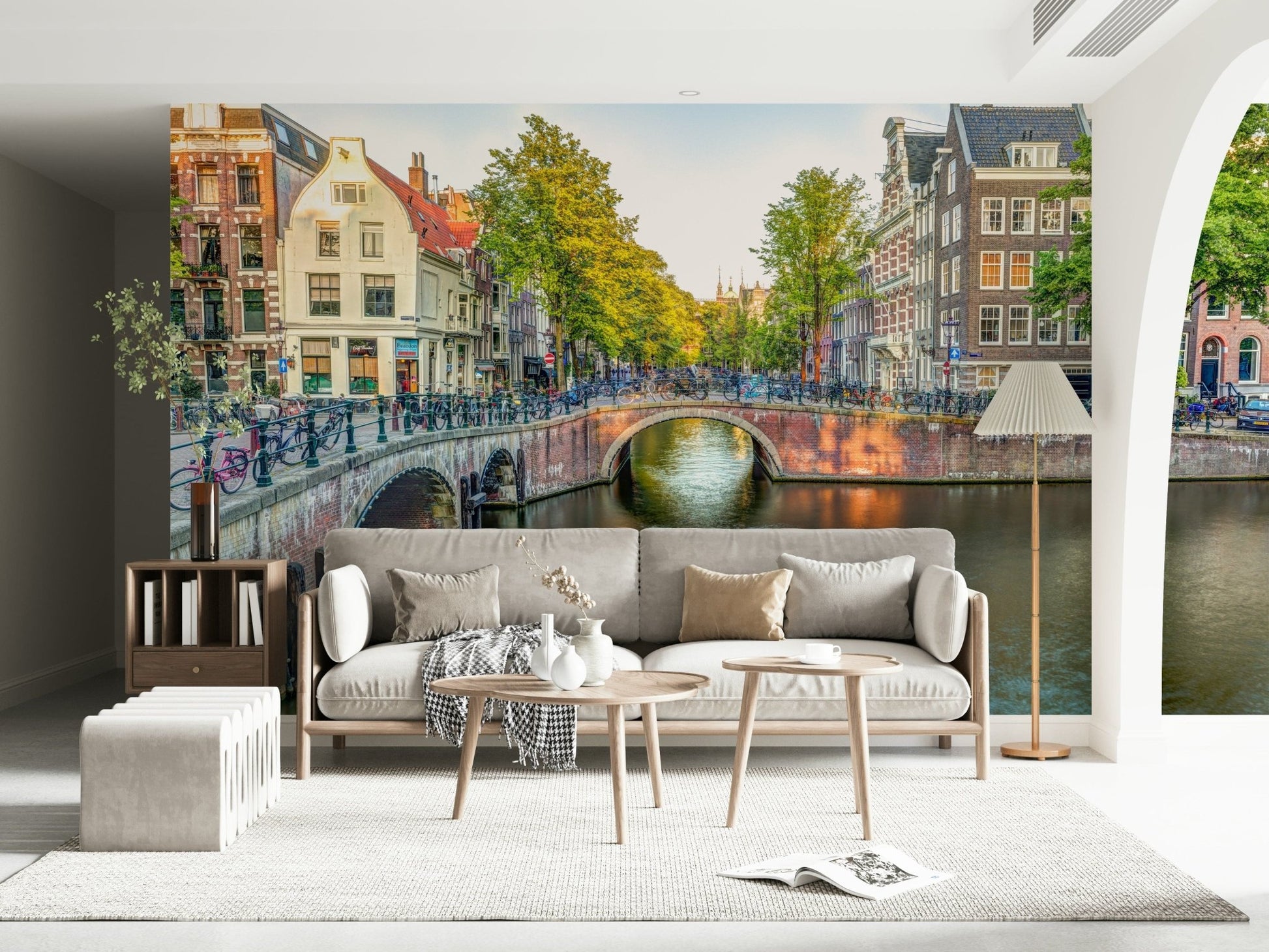 Visit Amsterdam wallpaper mural of an Amsterdam canal behind a gray sofa near an arched doorway in a living room