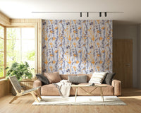 Warm Meadow Harmony wallpaper of amber and blue wildflowers behind a tan sofa in a sunlit wood-trimmed room