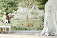 Watercolor Woodland Wonders wallpaper mural with a fox and deer beside a white canopy drape and plush bunny in a nursery