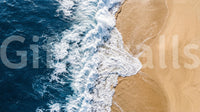Sea vs land wall mural with aerial surf lines cutting across warm golden sand textures