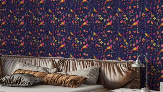 Whimsical Songbird Garden Navy wallpaper above a bed with satin gold and grey pillows and a vintage lamp