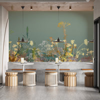 Wild Flower Design Art wallpaper mural in sage green with golden blooms in a cafe with rattan stools and white tables