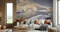 Arctic Dreamscape wallpaper mural of a snowy arctic coast behind a grey sofa with rust cushions in a living room