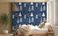 Minimalist tree illustrations and bright stars forming a festive pattern on navy wallpaper.