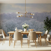 Winter's Whispers wallpaper mural of a misty frosted woodland behind a wood dining table and beige chairs